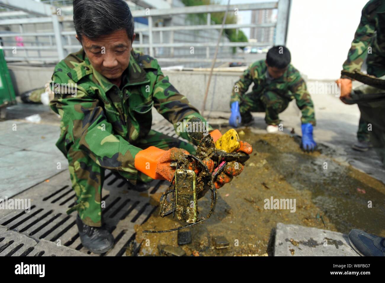 Chinese workers collect the mobile phones and sunglasses they found in a cesspit at the Wuhan Railway Station in Wuhan city, central China's Hubei pro Stock Photo