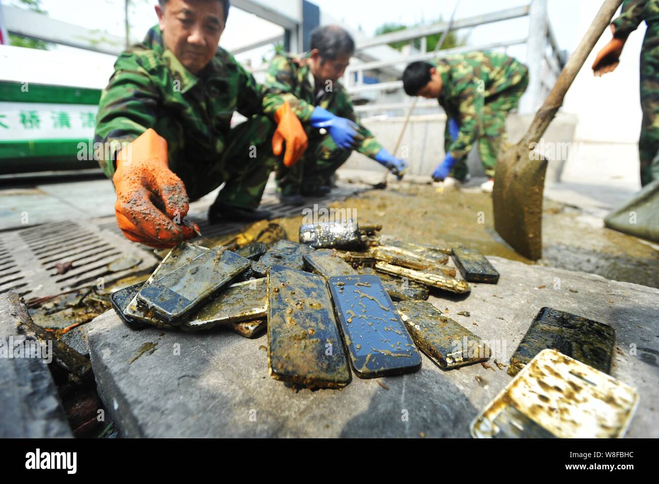 Chinese workers collect the mobile phones they found in a cesspit at the Wuhan Railway Station in Wuhan city, central China's Hubei province, 27 April Stock Photo
