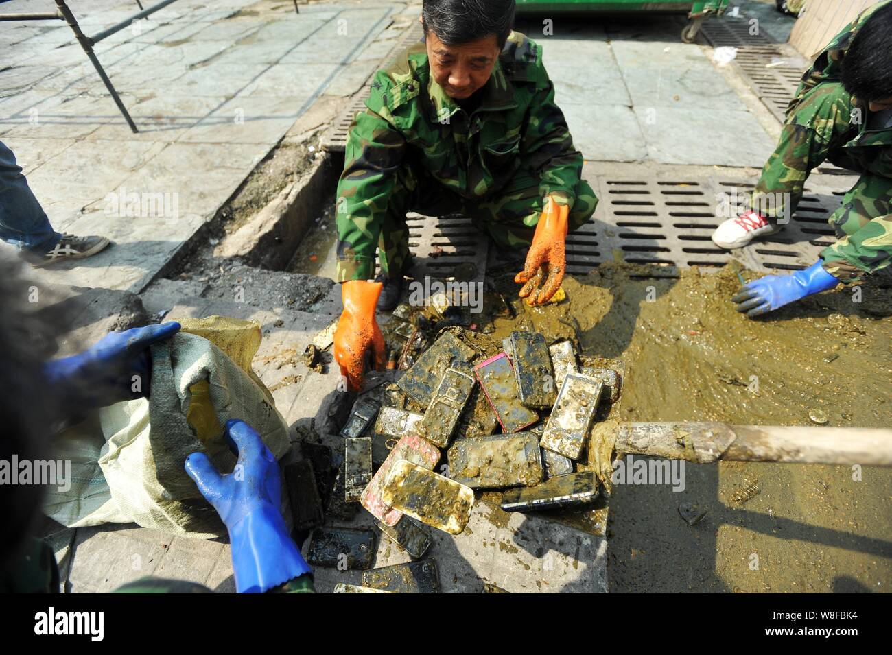 Chinese workers collect the mobile phones they found in a cesspit at the Wuhan Railway Station in Wuhan city, central China's Hubei province, 27 April Stock Photo