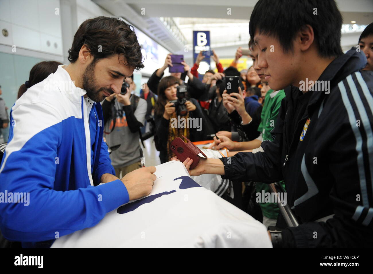 Spanish football star Raul Gonzalez Blanco of New York Cosmos, left, signs autographs for fans as he arrives at the Hong Kong International Airport in Stock Photo