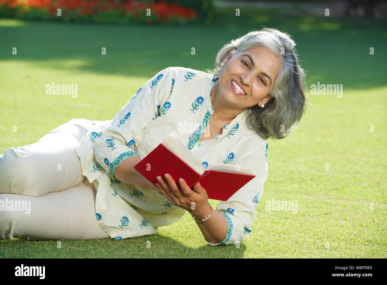 Senior woman reading a book in lawn Stock Photo - Alamy