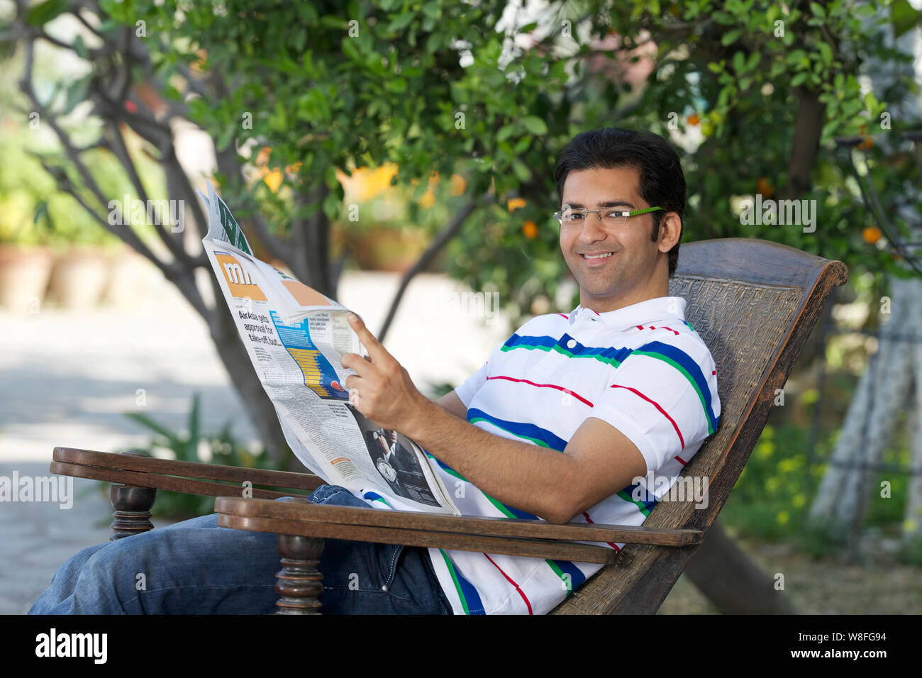 Young man reading a newspaper in garden Stock Photo - Alamy
