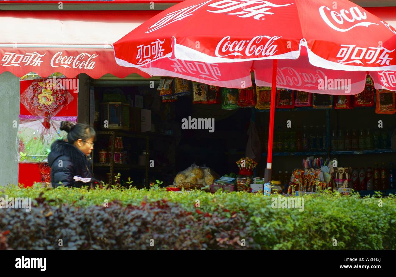 --FILE--A pedestrian walks past advertisements for Coca-Cola in Yichang ...