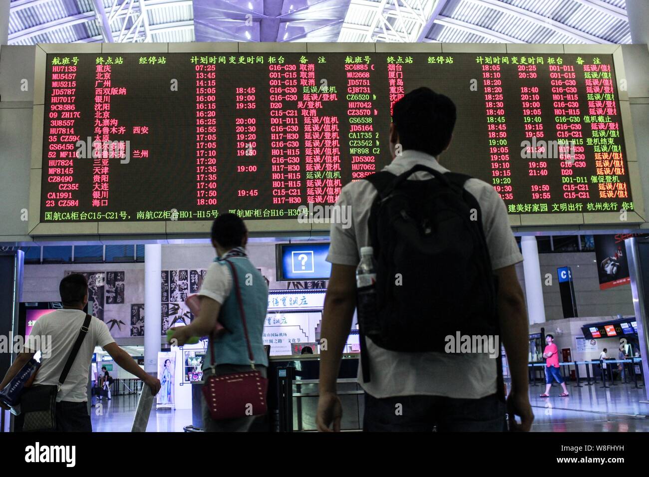 --FILE--Chinese passengers look at a display showing departure information of flights most of which are canceled or delayed at the Xiaoshan Internatio Stock Photo