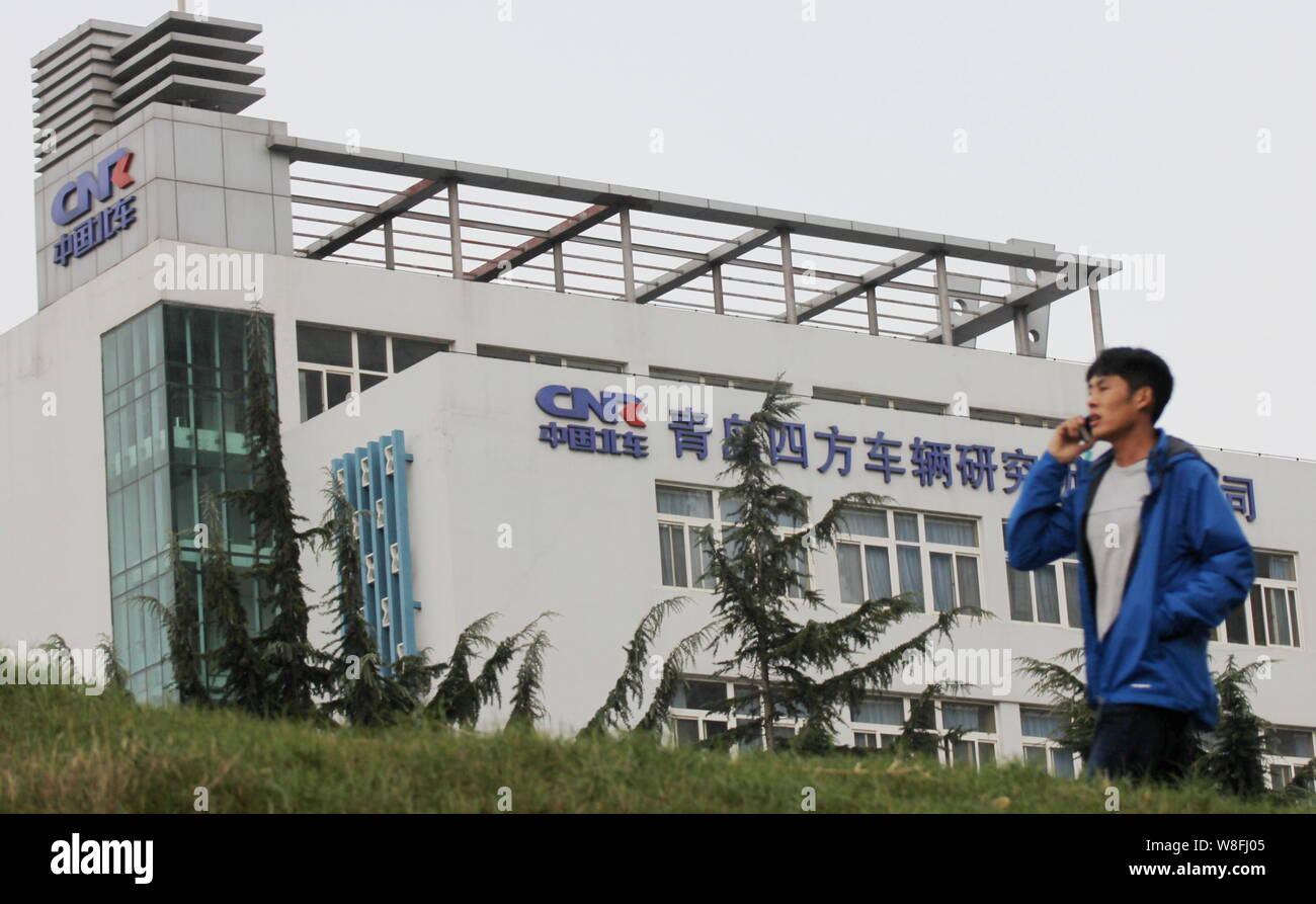 --FILE--A pedestrian talks on his mobile phone as he walks past the office building of CNR Sifang Rolling Stock Research Institute in Qingdao city, ea Stock Photo