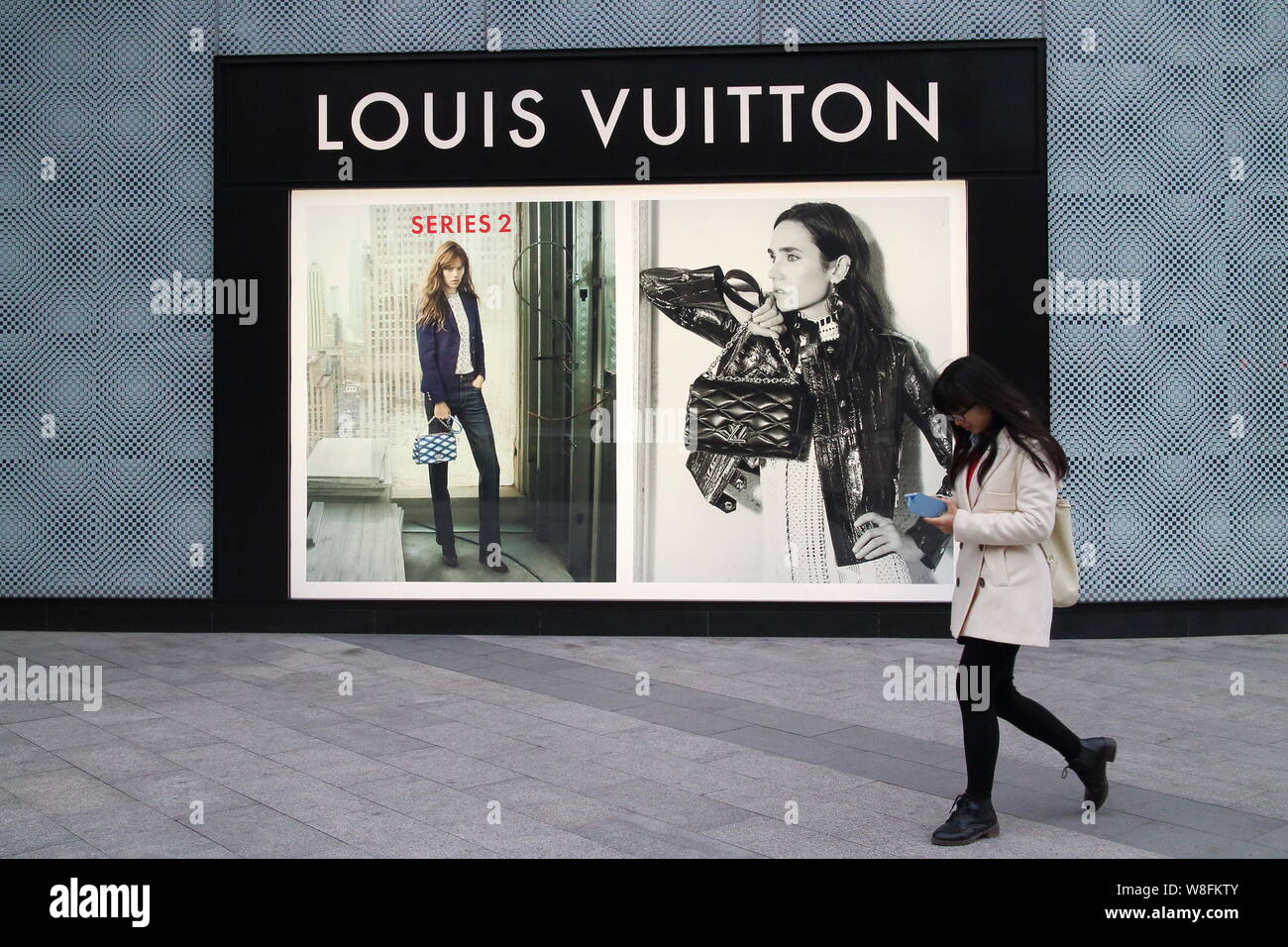 FILE--A young woman walks past a fashion boutique of Louis Vuitton (LV) in  Fuzhou city, southeast China's Fujian province, 7 March 2015. To counte  Stock Photo - Alamy