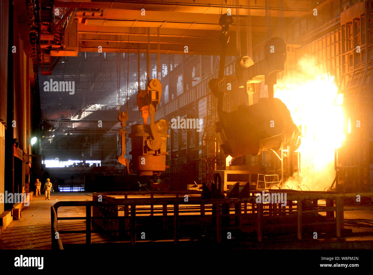 --FILE--Chinese workers survey the production of steel next to a furnace containing molten steel at a steel plant in Huaian city, east China's Jiangsu Stock Photo