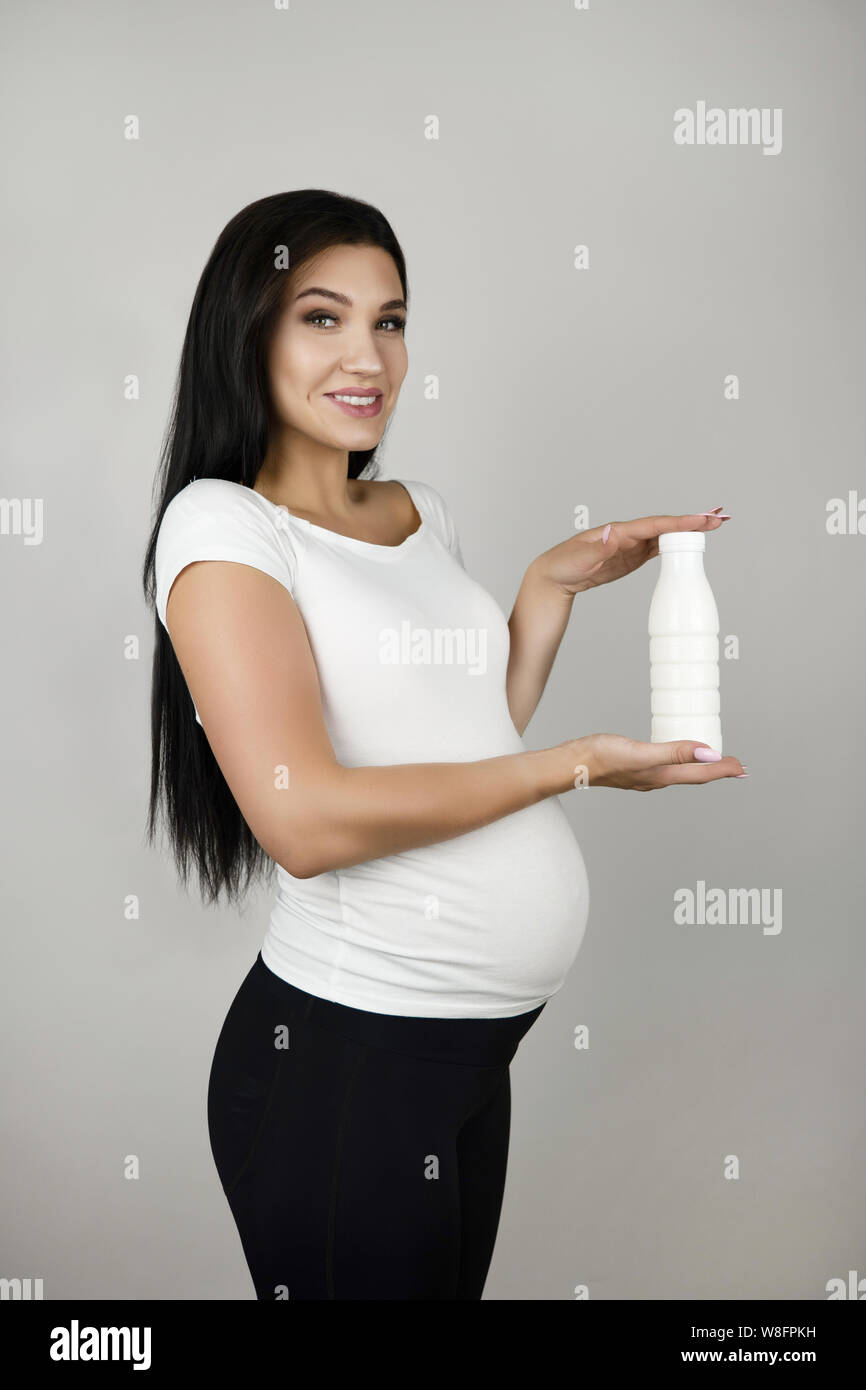 beautiful pregnant woman holding bottle with kefir yogurt