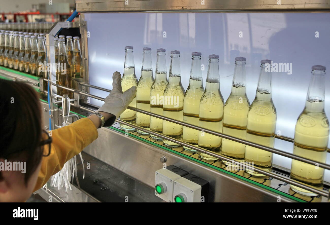 --FILE--A Chinese worker checks beer on a production line at a brewery ...