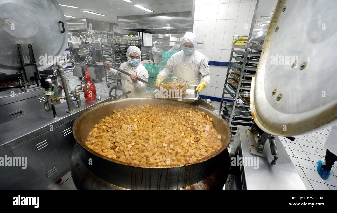 Chinese workers cook food at a food processing plant of Beijing Jingtie ...
