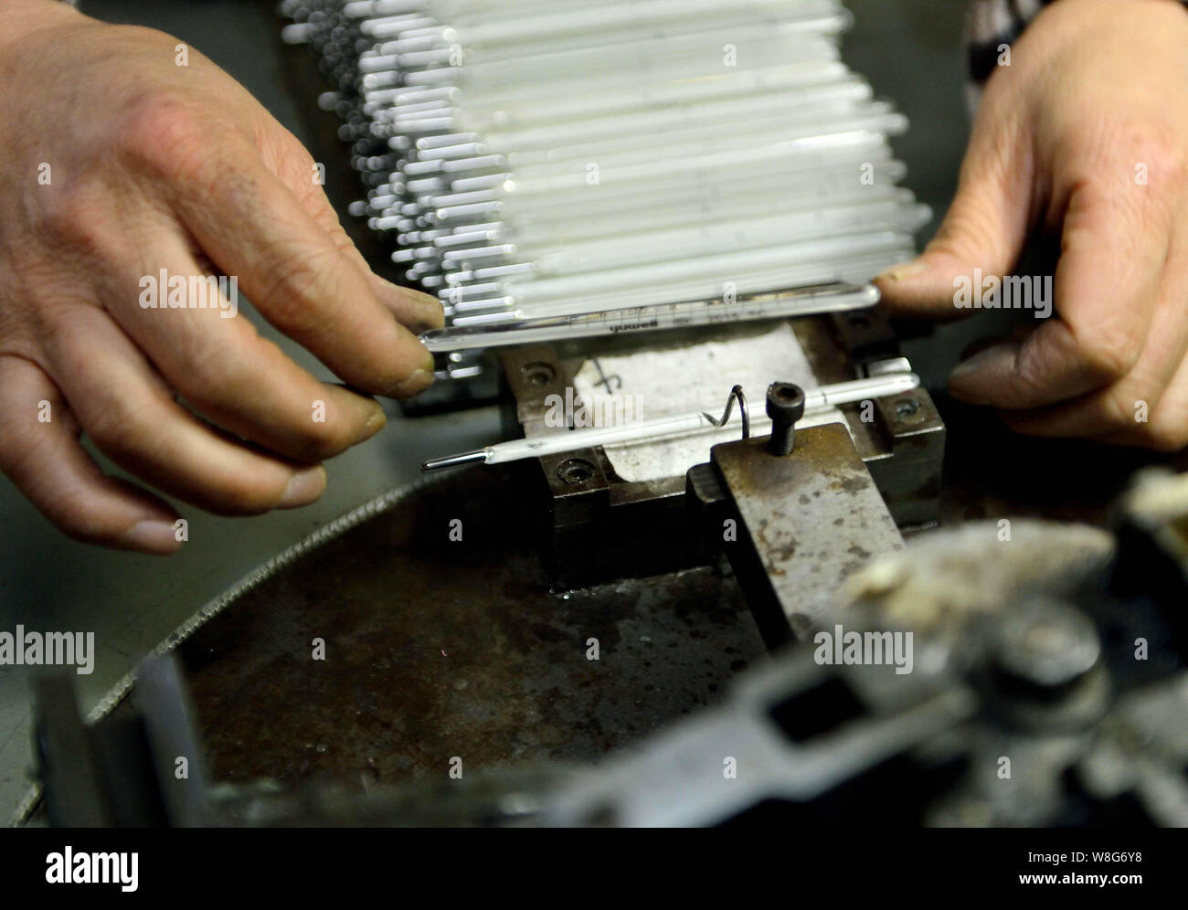 A Chinese worker has tubes of mercury-in-glass thermometers printed at the plant of Jiangsu Yuyue Medical Equipment & Supply Co., Ltd. in Yancheng cit Stock Photo