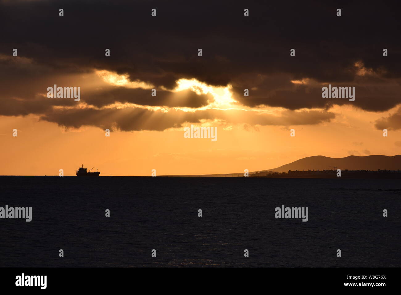 Ship silhouetted on the horizon at sunset with dramatic skies, Arrecife, Lanzarote Stock Photo