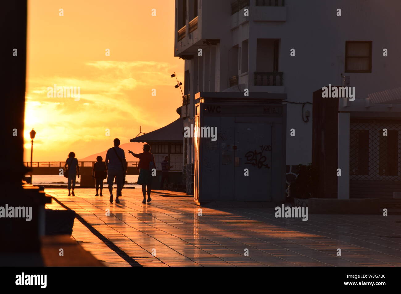 People enjoy sunset golden hour on the seafront promenade of Arrecife, Lanzarote - Stock Image