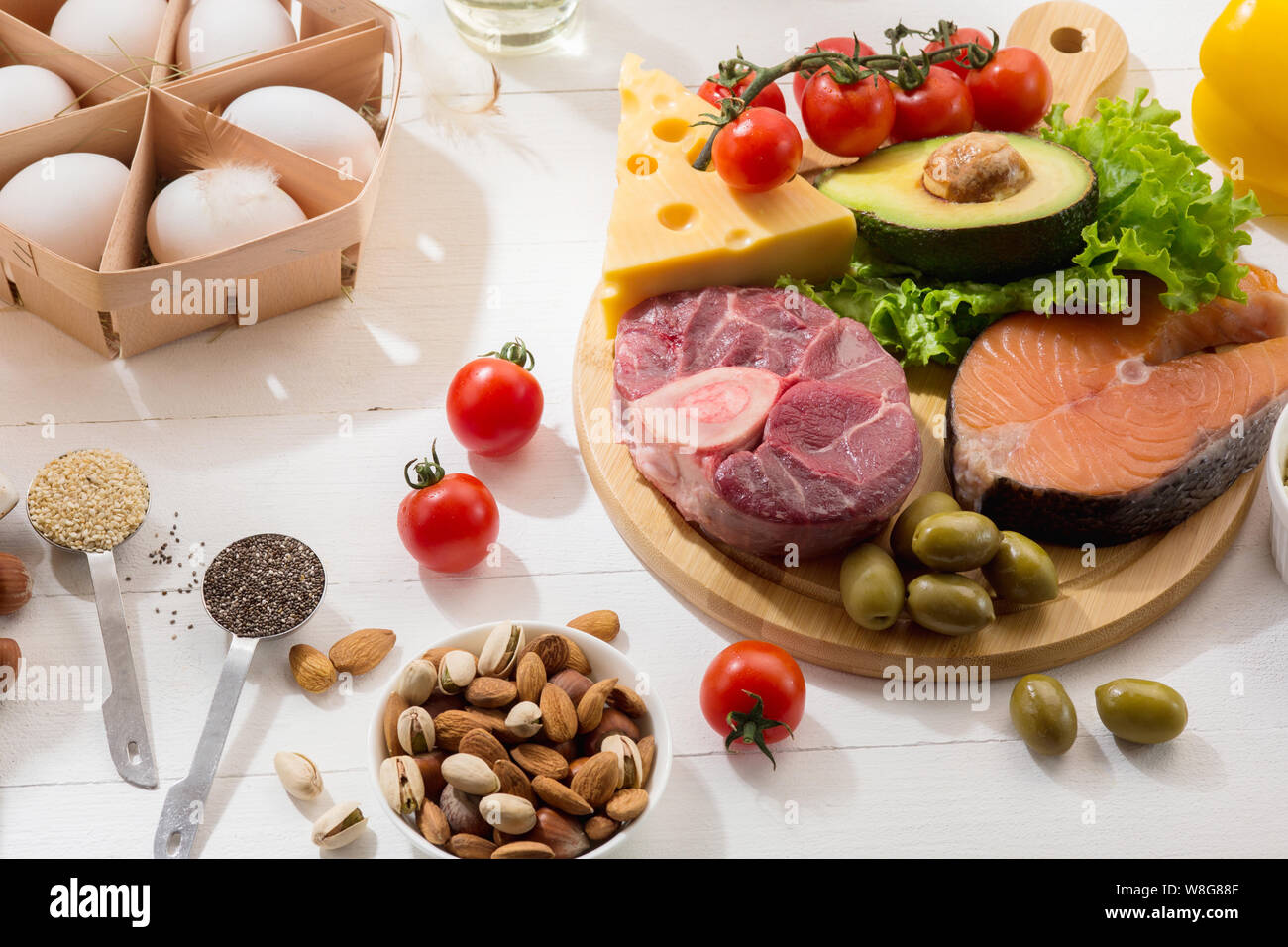 Ketogenic low carbs diet - food selection on white wooden background. Balanced healthy organic ingredients of high content of fats. Nutrition for the heart and blood vessels. Meat, fish and vegetables. Stock Photo