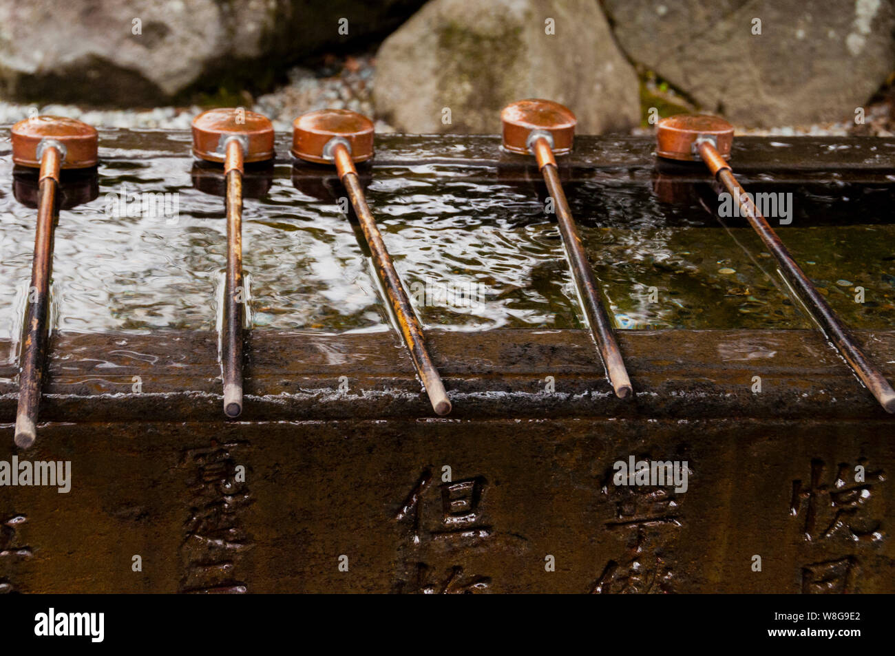 Copper ladles and stone Japanese water basin with etched Japanese