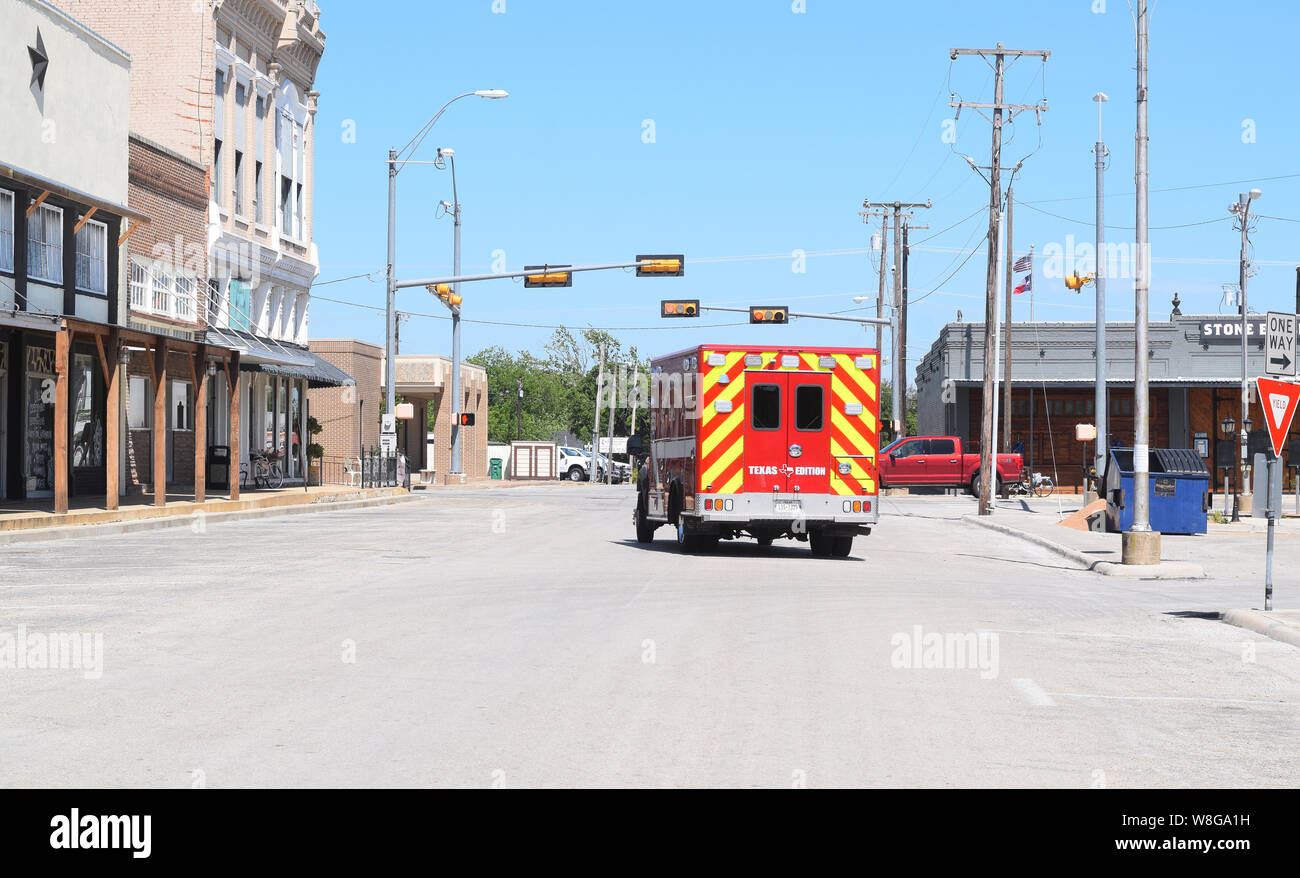 Ambulance drives down street on the town square of Comanche Texas Stock Photo
