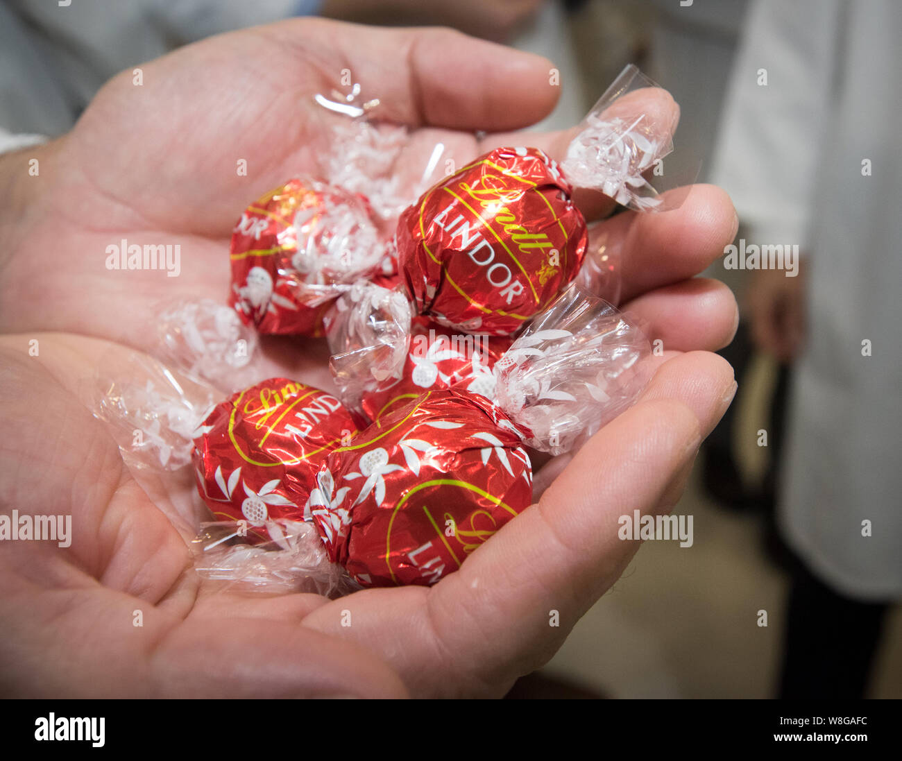 Man holding a handful of individually wrapped Lindt Lindor candies Stock Photo