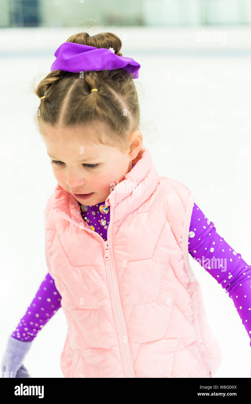 Little girl practicing figure skating in a purple dress with crystals