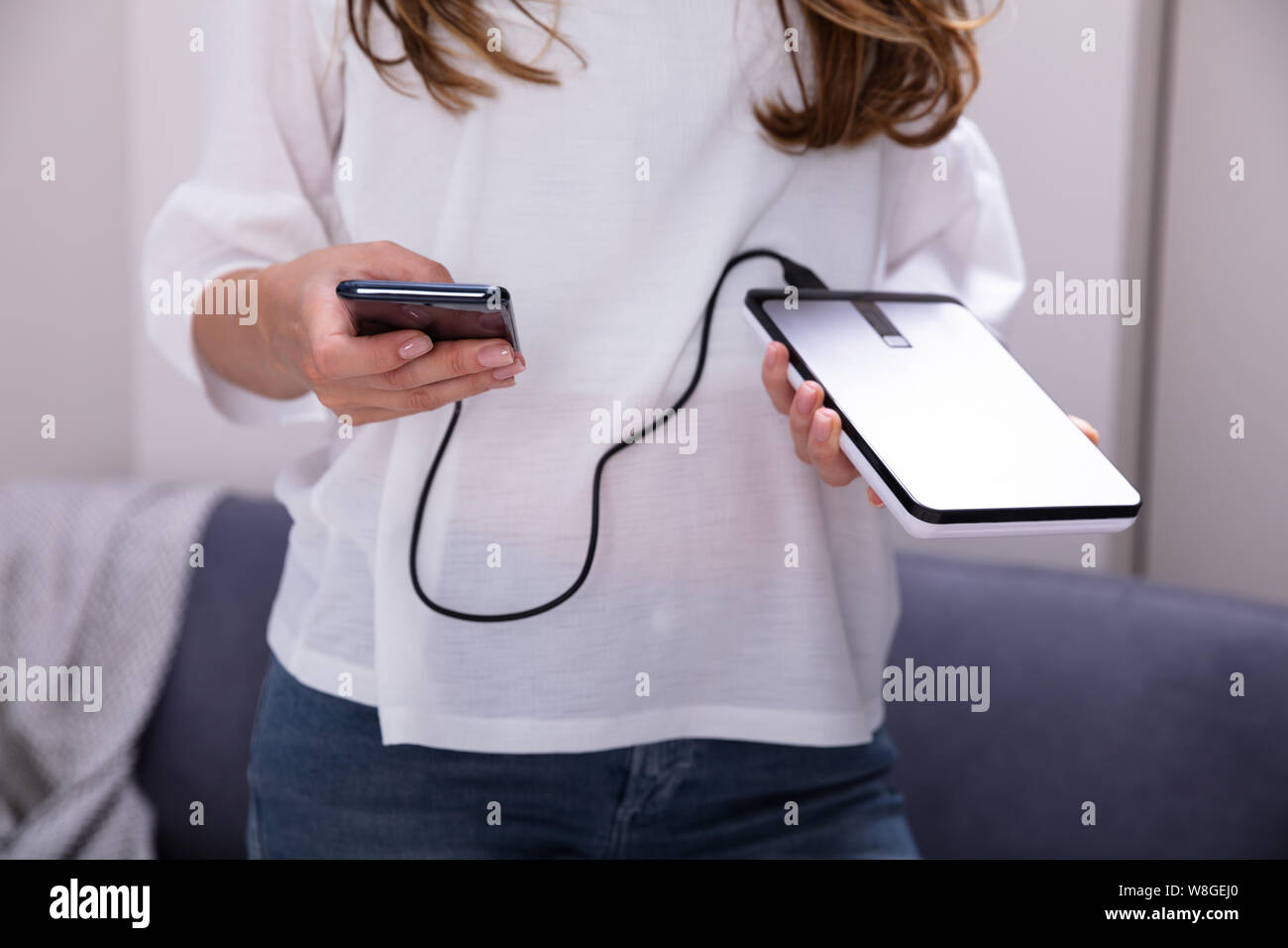 Mid-section Of Woman Using External Hard Disk For Data Transfer Stock Photo
