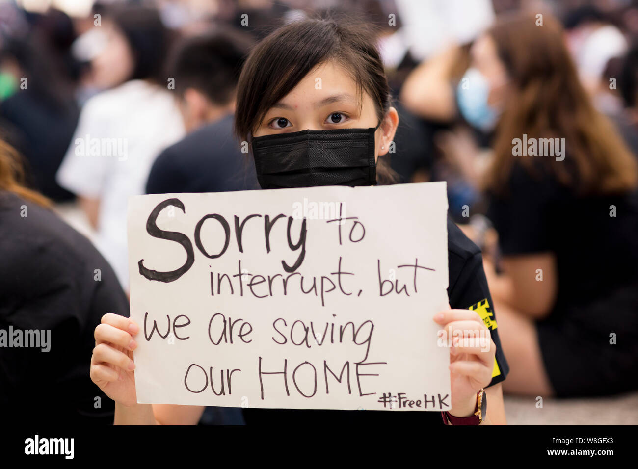 A female protester holding a message to apologise to the travellers for the inconvenience they have causes due to the protest.Thousands of protesters took to the arrival hall of the Hong Kong international airport under the name 'Greetings from HKers Assembly' to catch the attention by the international travelers who just landed in Hong Kong about the current unrest situation in the city. Stock Photo