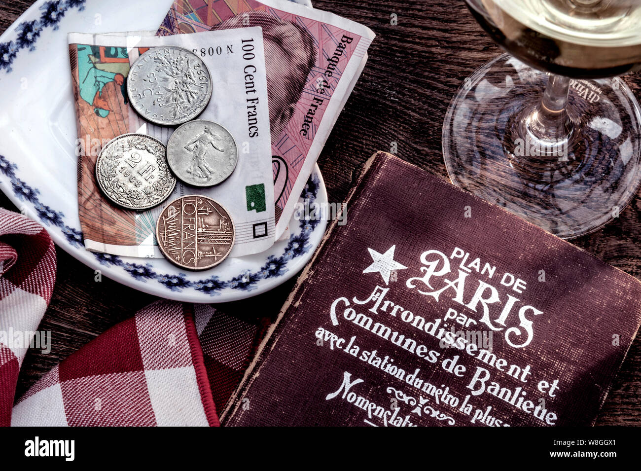 Vintage retro Paris café 50’s 60’s retro travel Paris vintage holiday France French Francs currency bill payment vintage travel 1950s-1960's retro French travel, Art Deco style Paris guide book, French Francs, wine glass on sunlit restaurant table Stock Photo