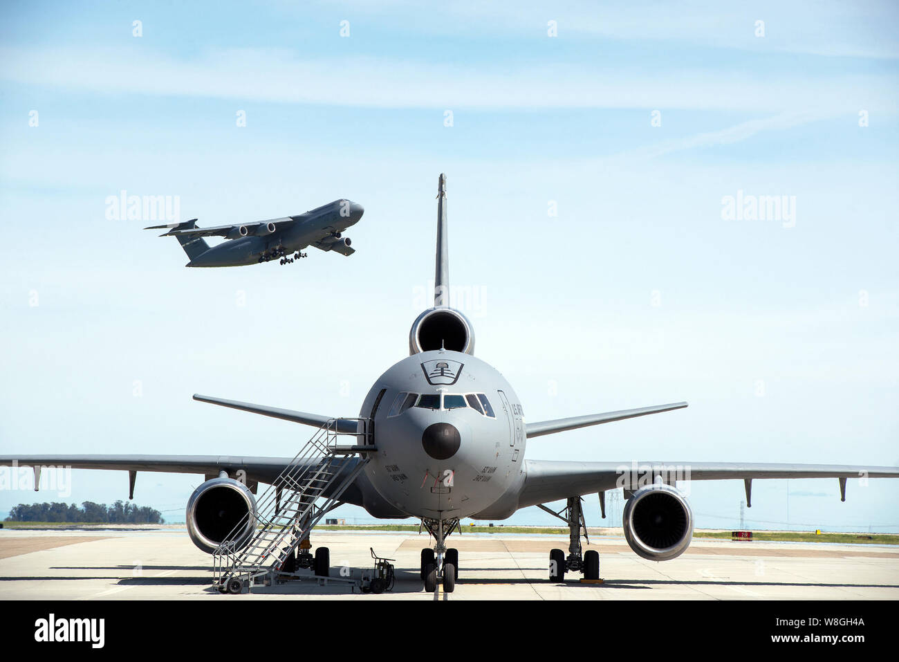 A KC-10 Extender is parked on the ramp as a C-5M Super Galaxy takes off at Travis Air Force Base, Calif., March 16, 2017. Stock Photo