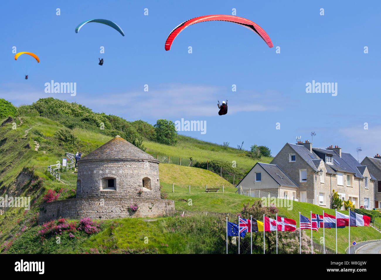 Flying / soaring paragliders above the 17th century Tour Vauban tower at Port-en-Bessin-Huppain along the English Channel, Calvados, Normandy, France Stock Photo