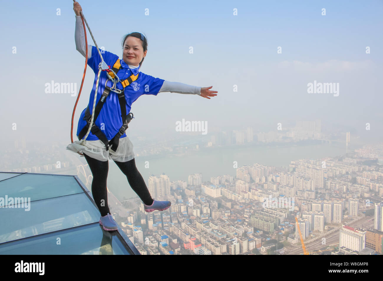 A tourist poses on the 303-meter-high glass skywalk built on the 76th floor of the Yunding Building in Liuzhou city, south China's Guangxi zhuang Auto Stock Photo