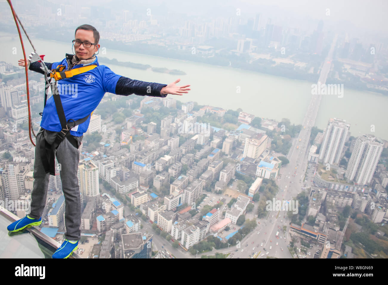 A tourist poses on the 303-meter-high glass skywalk built on the 76th floor of the Yunding Building in Liuzhou city, south China's Guangxi zhuang Auto Stock Photo