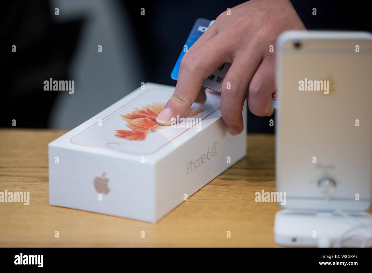 A customer prepares to buy a rose gold iPhone 6s smartphone at the Apple Store near the West Lake in Hangzhou city, east China's Zhejiang province, 25 Stock Photo