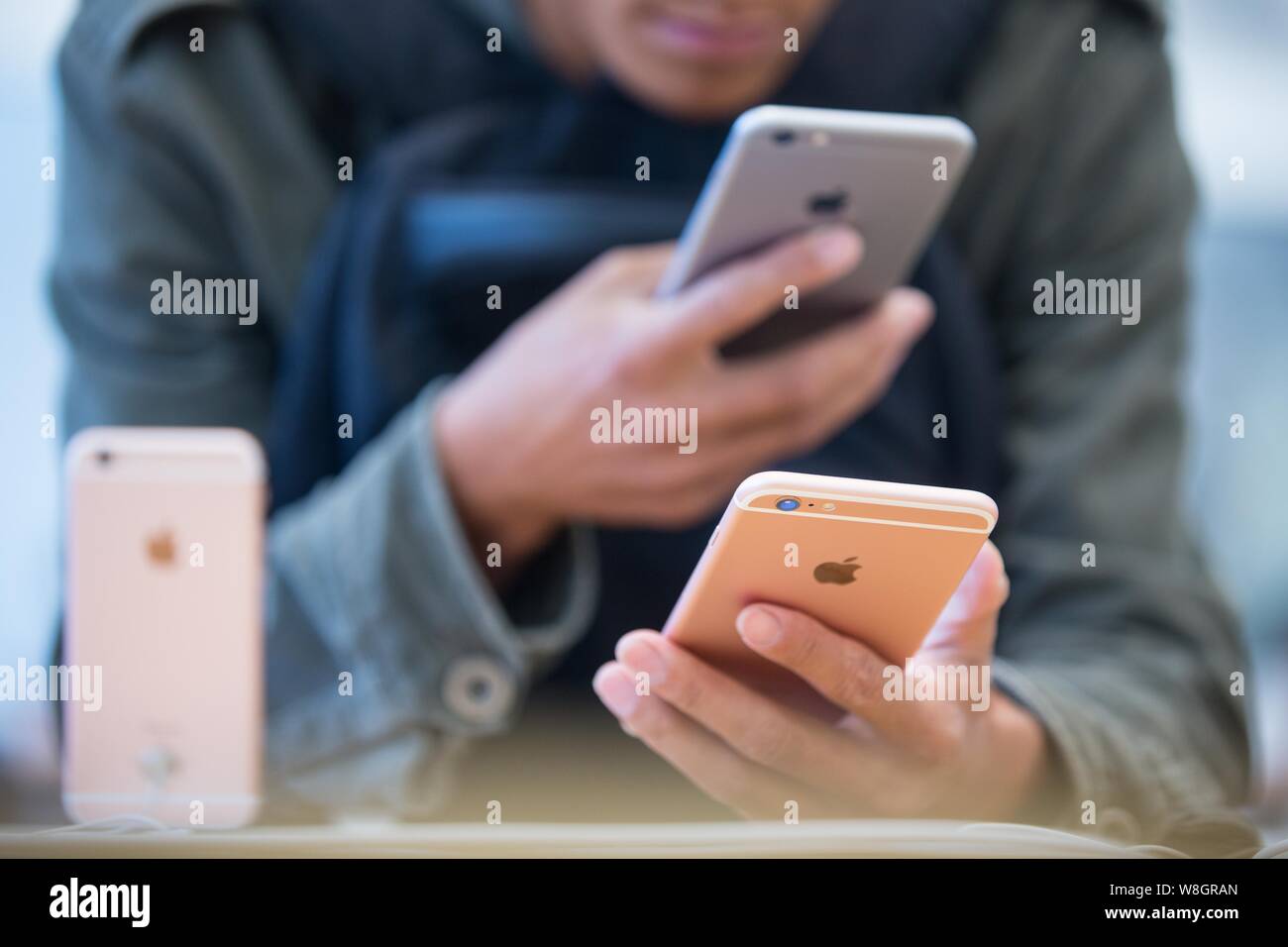 A customer tries out an iPhone 6s smartphone and a rose gold iPhone 6s Plus smartphone at the Apple Store near the West Lake in Hangzhou city, east Ch Stock Photo