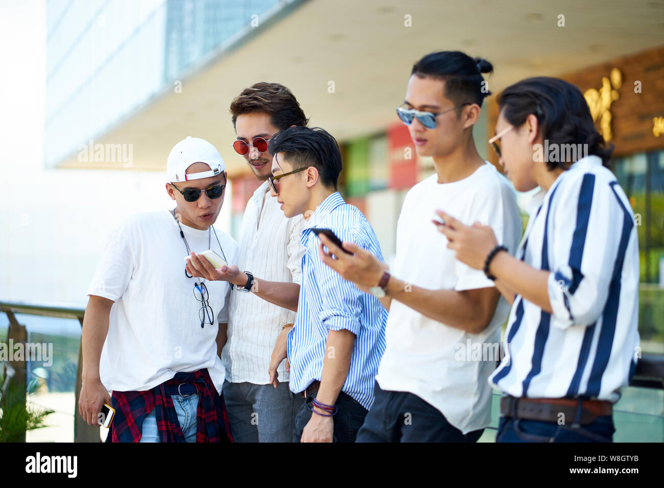 young asian adult men using social media looking at mobile phone together Stock Photo