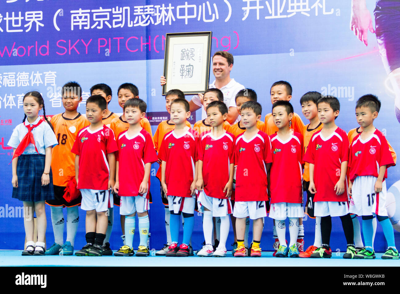 Retired English football star Michael Owen, back, poses with children at the opening ceremony for the SoccerWorld Summer Football Festival in Nanjing Stock Photo
