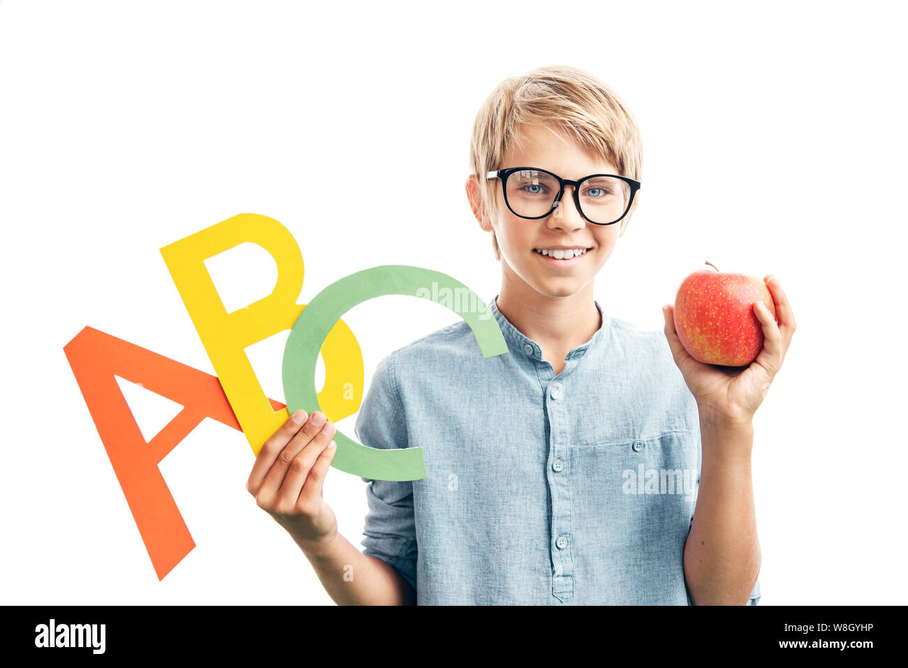 Smiling kid in glasses holding English letters and an apple Stock Photo