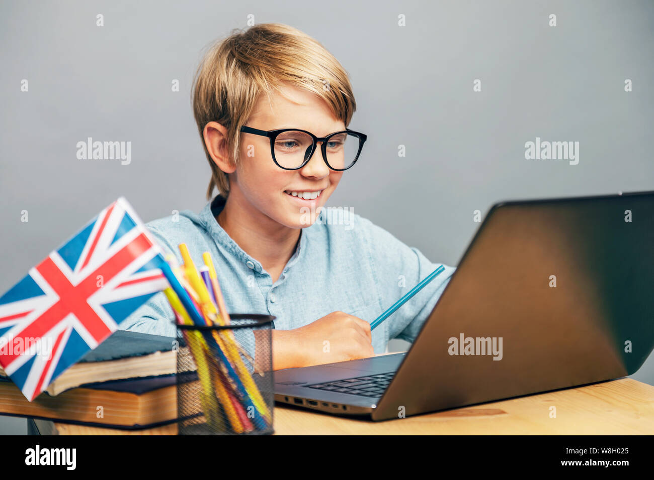 Smiling schoolboy in glasses studying English by the laptop Stock Photo