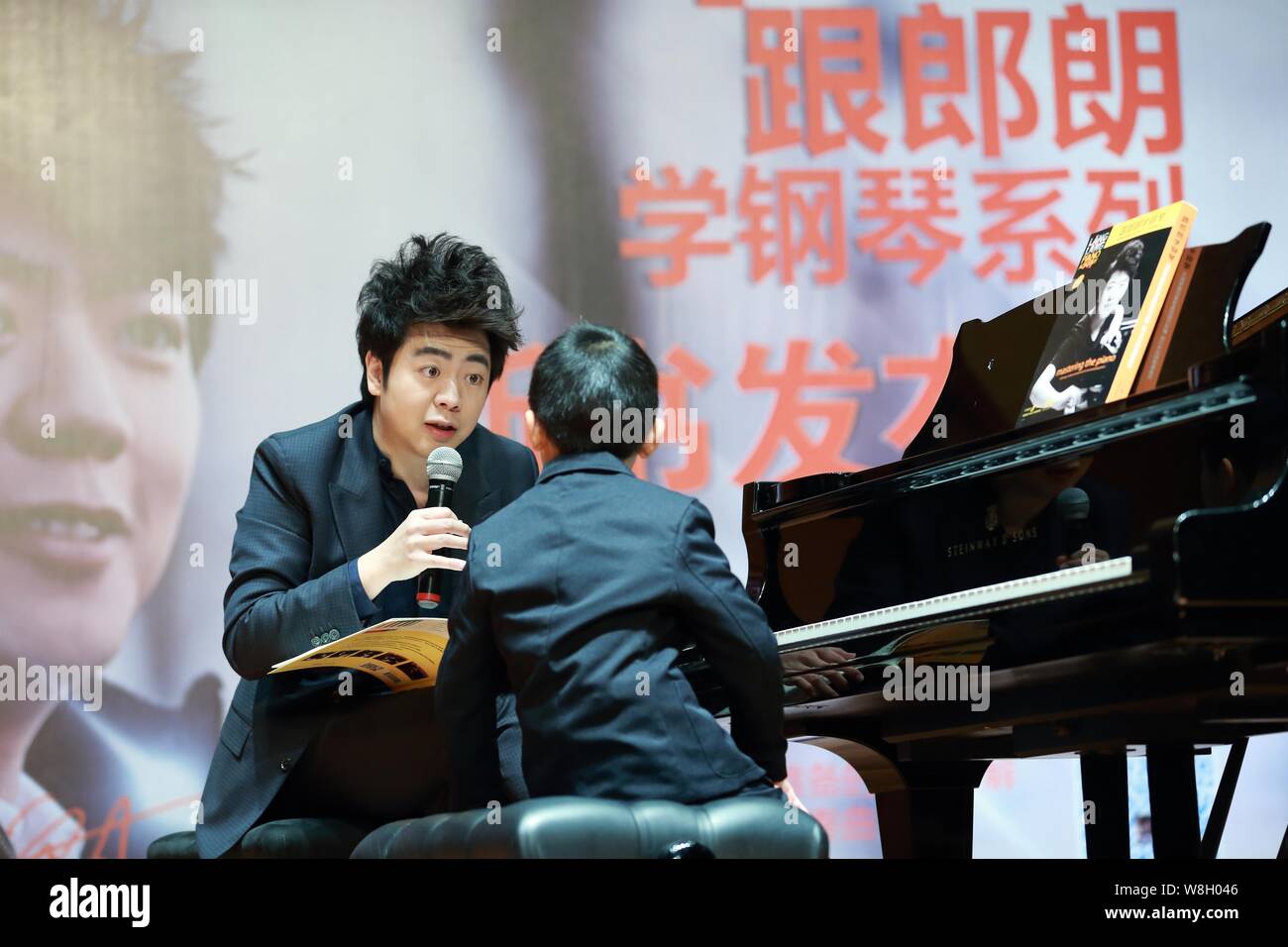 Chinese pianist Lang Lang, left, teaches a young boy at a press conference for his new book 'Lang Lang Piano Academy: Mastering the Piano' in Shanghai Stock Photo