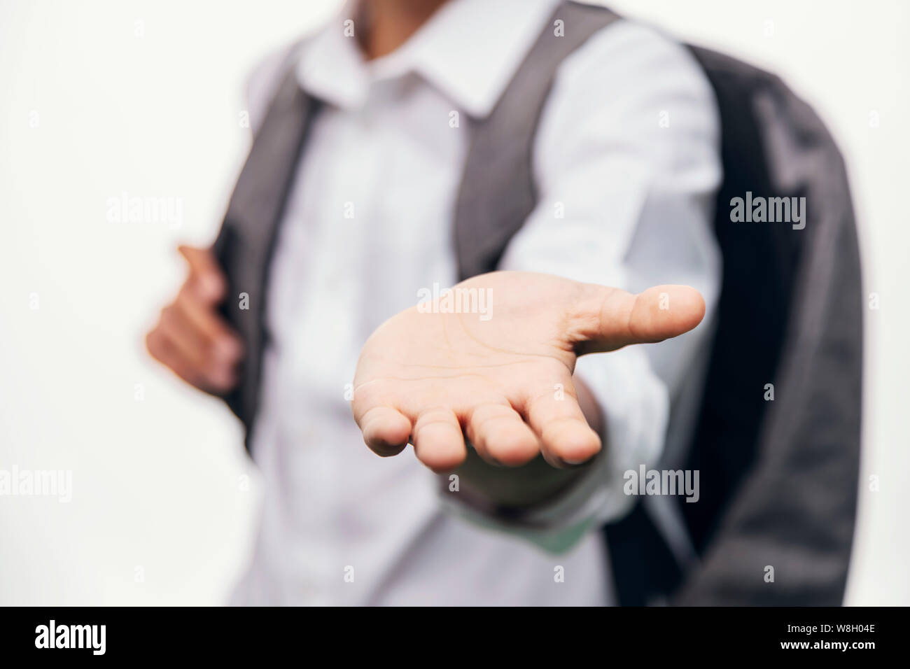 Schoolboy with backpack stretching hand with an opened palm Stock Photo