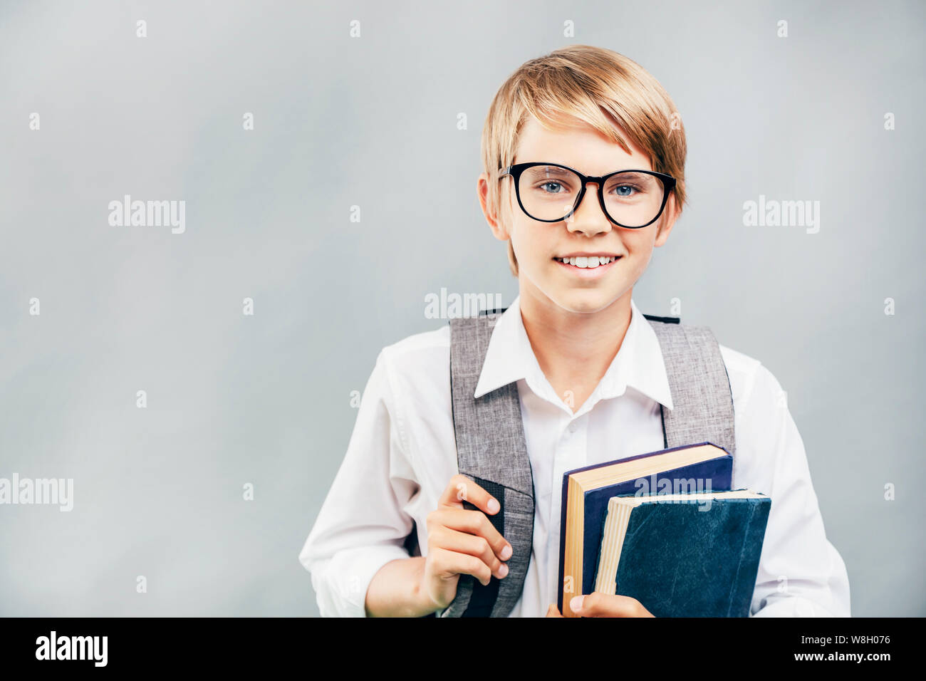 Cheerful pupil in glasses carrying books and a schoolbag Stock Photo