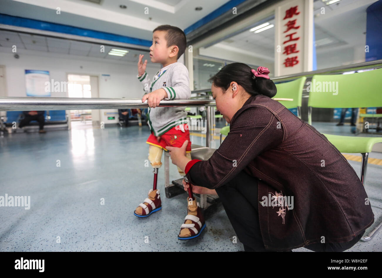 The mother of the four-year-old legless boy Xiao Feng helps him to remove the temporary prosthetic legs at the Disabled Rehabilitation Center of Hubei Stock Photo