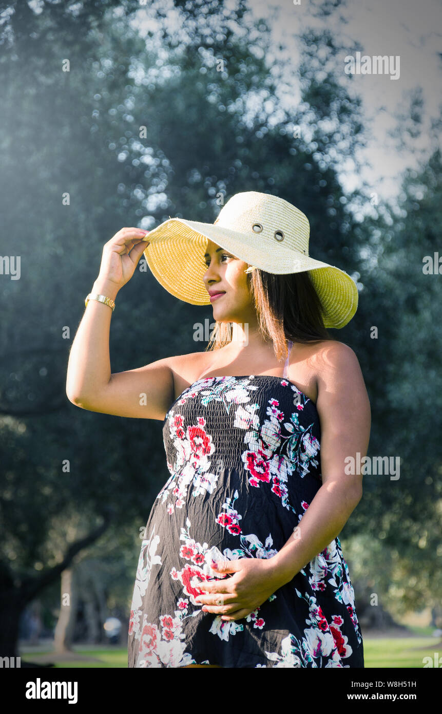 Pregnant Peruvian woman in a forest, beautiful young Peruvian girl waiting for a child, a naughty woman with dark hair in dress with hat on nature Stock Photo