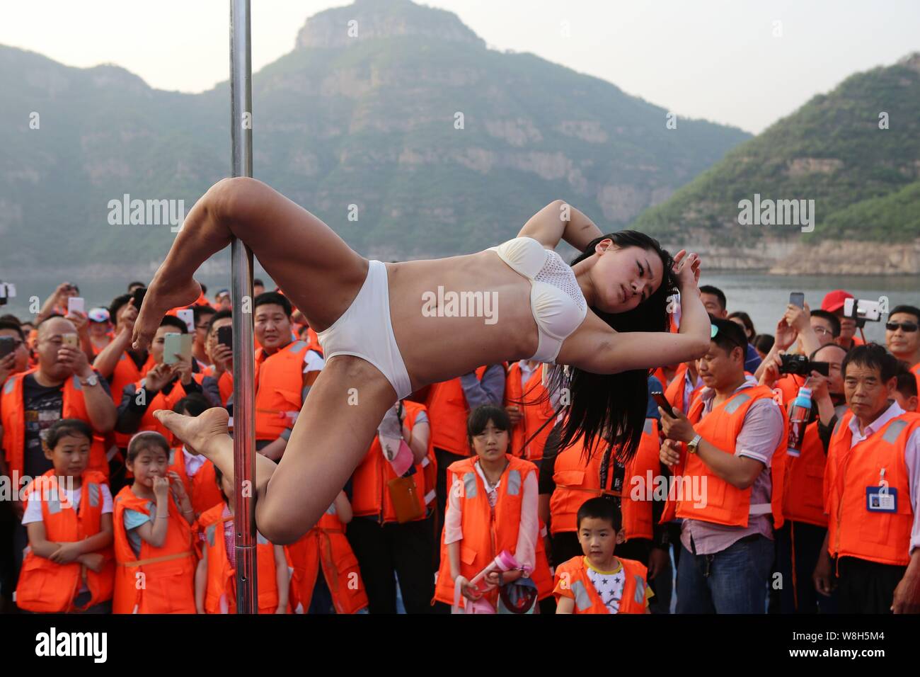 Tourists enjoy pole dancing performed by Liu Feifei, a pole dancer, on a cruise at Three Gorges of the Yellow River scenic spot in Jiyuan city, centra Stock Photo