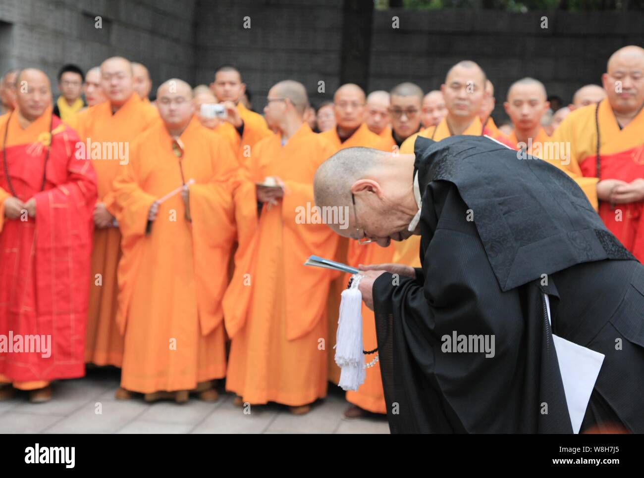 Japanese monk Yoshio Hasegawa, front, bows after chanting scriptures during a memorial to mourn for the victims of the Nanjing Massacre at the Museum Stock Photo