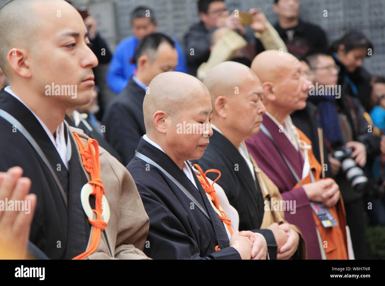 Chinese and foreign monks observe a moment of silence during a memorial to mourn for the victims of the Nanjing Massacre at the Museum of Victims in N Stock Photo
