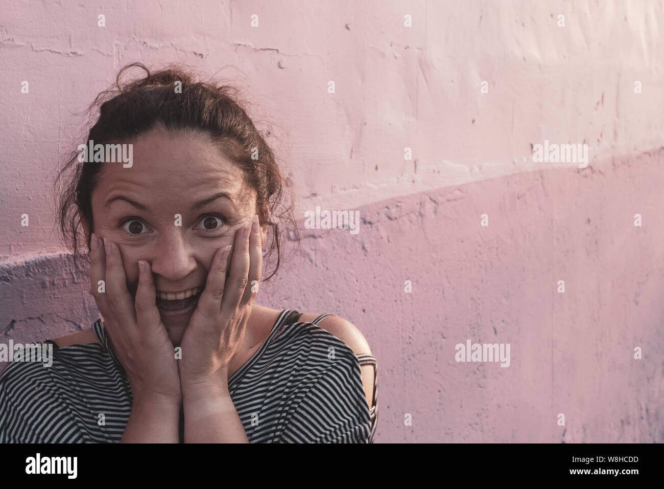 The surprised face of a beautiful girl standing near the wall. Eyebrows