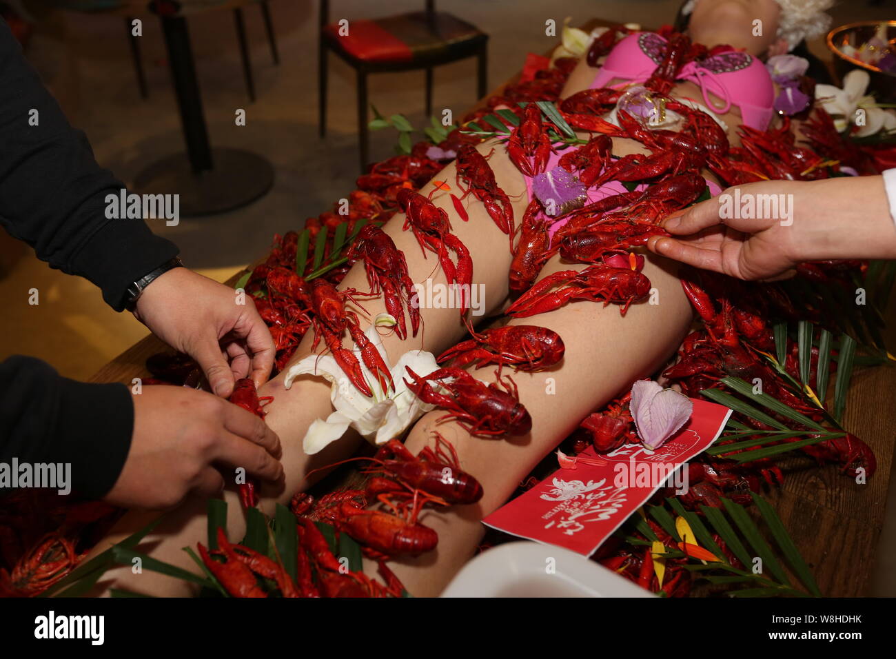 Chinese employees place crayfish on the body of a bikini-dressed model at a...