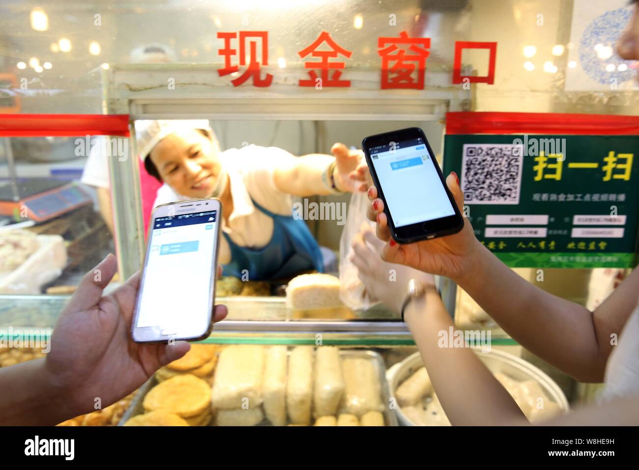 Chinese customers get their purchases after paying via mobile payment service Alipay of Alibaba Group on their smartphones at a free market in Wenzhou Stock Photo