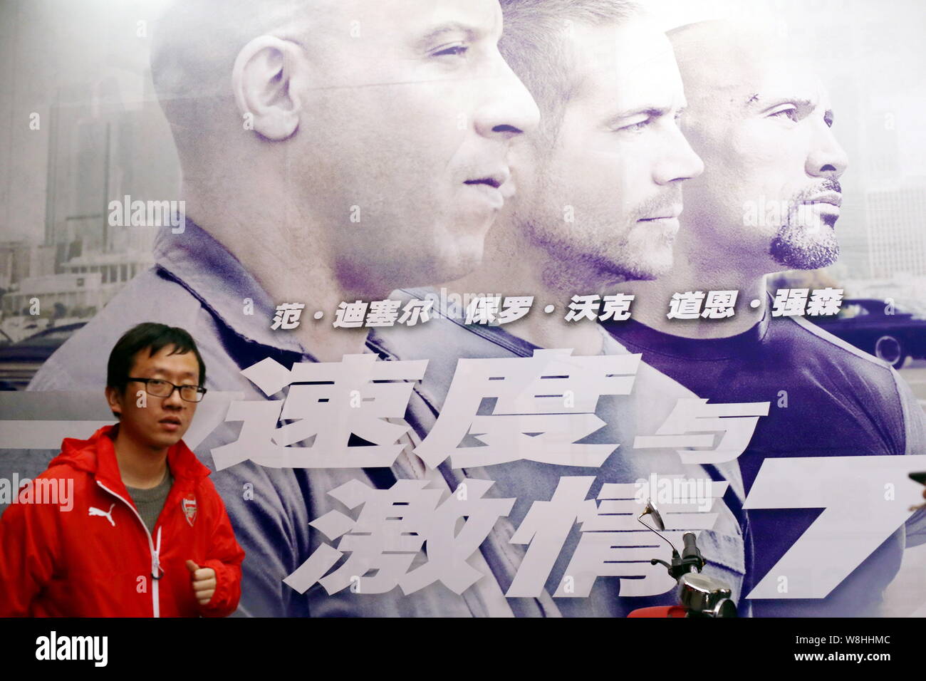 A Chinese filmgoer walks past a poster of the movie "Furious 7" at a