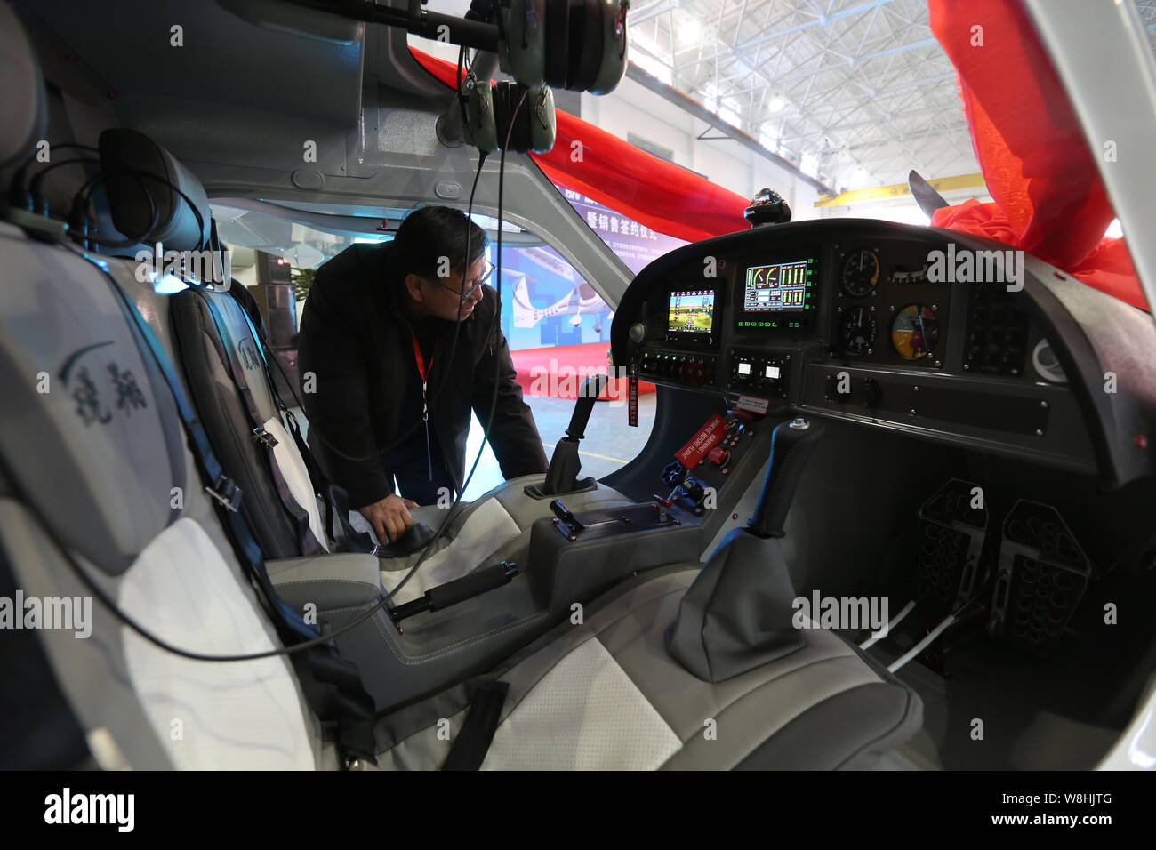A visitor looks at the interior of China's first electric light sport aircraft RX1E Ruixiang on display during the sales contract signing ceremony at Stock Photo