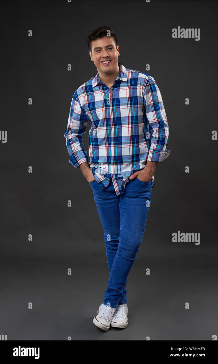 Young man in jeans standing on gray studio background Stock Photo