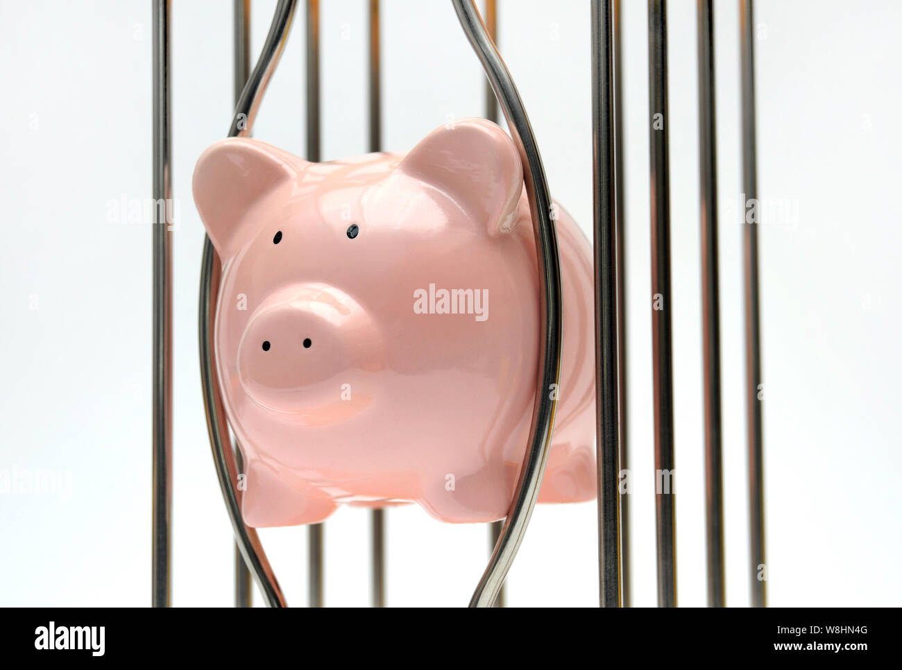 PIGGY BANK TRAPPED BETWEEN CAGE BARS RE SAVINGS FINANCE RETIREMENT PENSIONS ETC UK Stock Photo